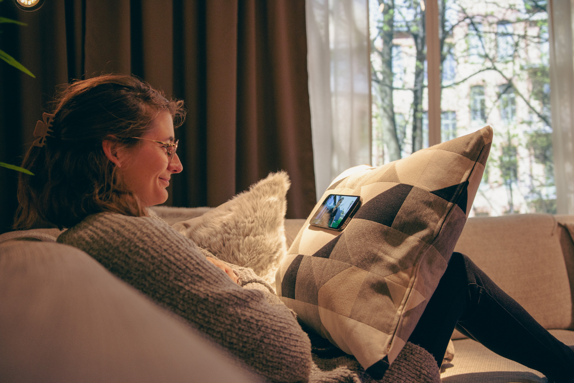 Woman watching a phone mounted on a cushion with MoMag at home