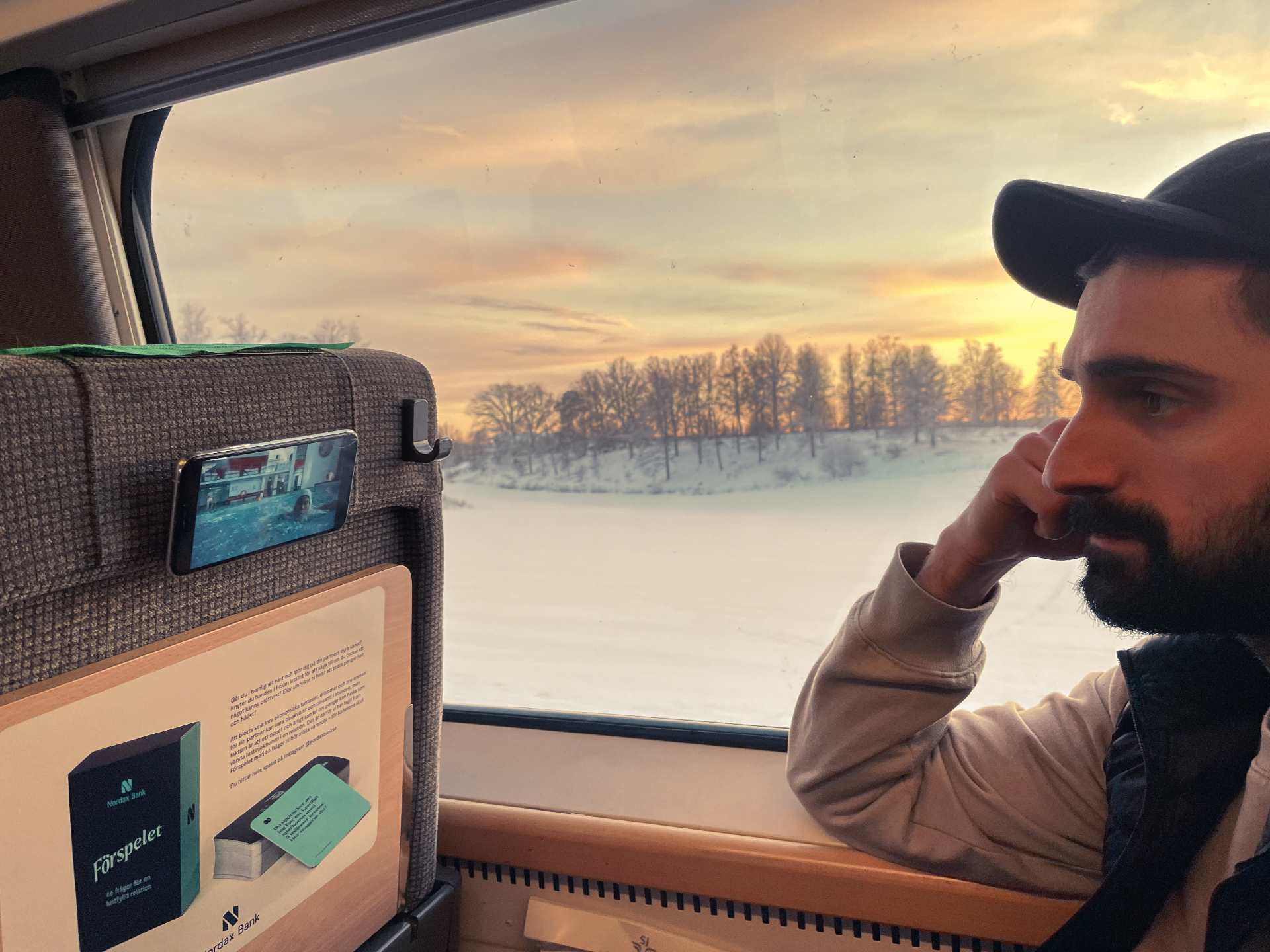 Traveller watching a phone mounted with MoMag on a train seat at sunset
